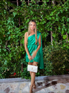 Woman in a green dress standing in front of a lush green wall.