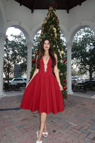 Woman in a red dress standing in front of a decorated Christmas tree.